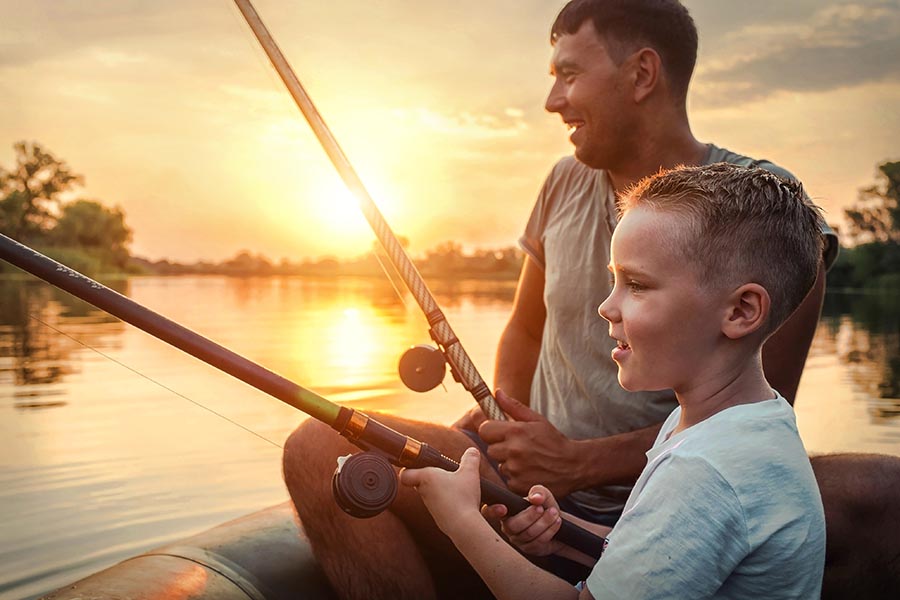 About Our Agency - Father and Son Fishing on a Lake at Sunset, Both Laughing