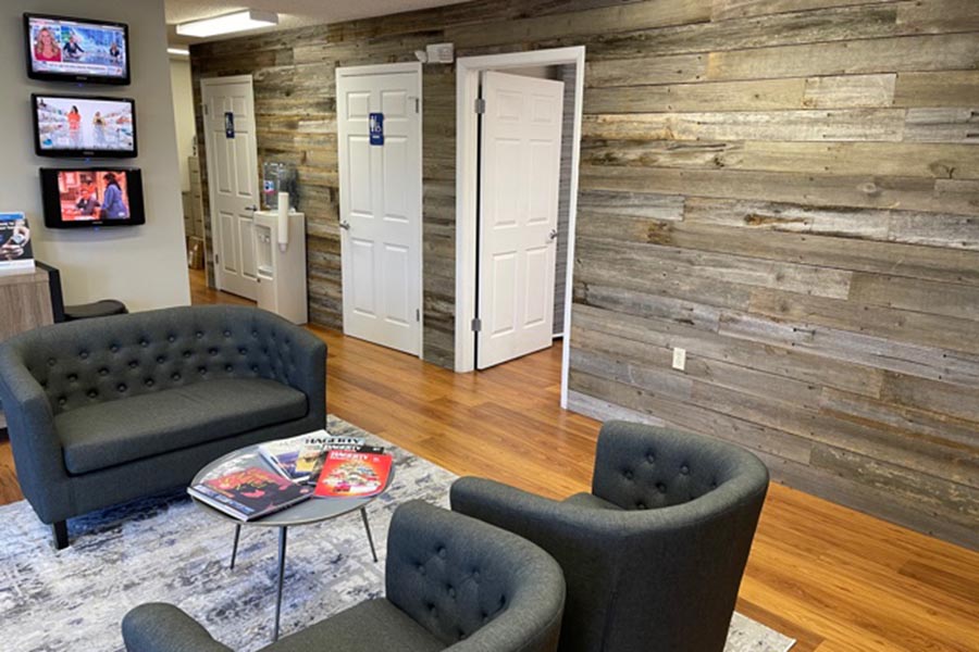 Contact - Bill Lovell Insurance Office Interior with Gray Furniture in a Waiting Area and Wood Paneled Walls